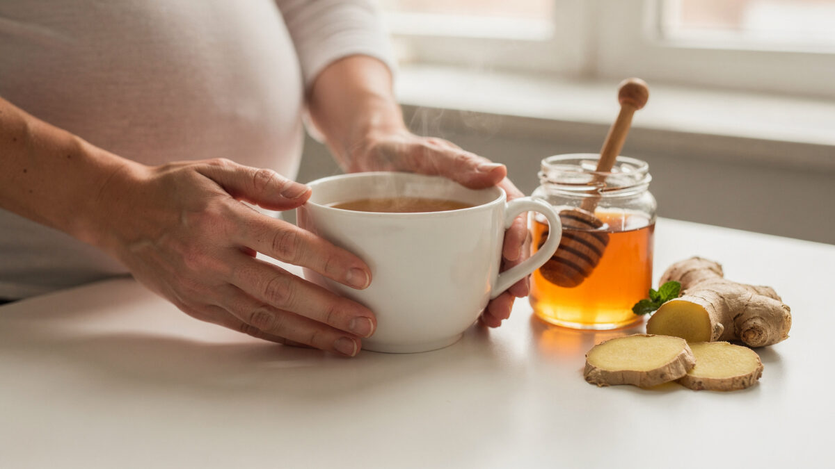 Schwangere Frau trinkt Kräutertee mit Ingwer und Honig gegen Erkältung – sichere Hausmittel in der Schwangerschaft