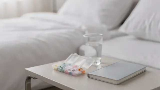 Bedside table mit Pillenbox, Wasserglas und Schlafprotokoll zum Thema Schlafmittel rezeptpflichtig